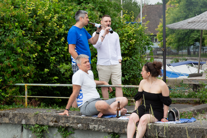 Menschen sitzen und stehen am Steg mit Getränken Menschen sitzen und stehen am Steg mit Getränken