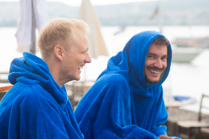Zwei Männer lachen in blauen Ponchos am Zürichsee Zwei Männer lachen in blauen Ponchos am Zürichsee